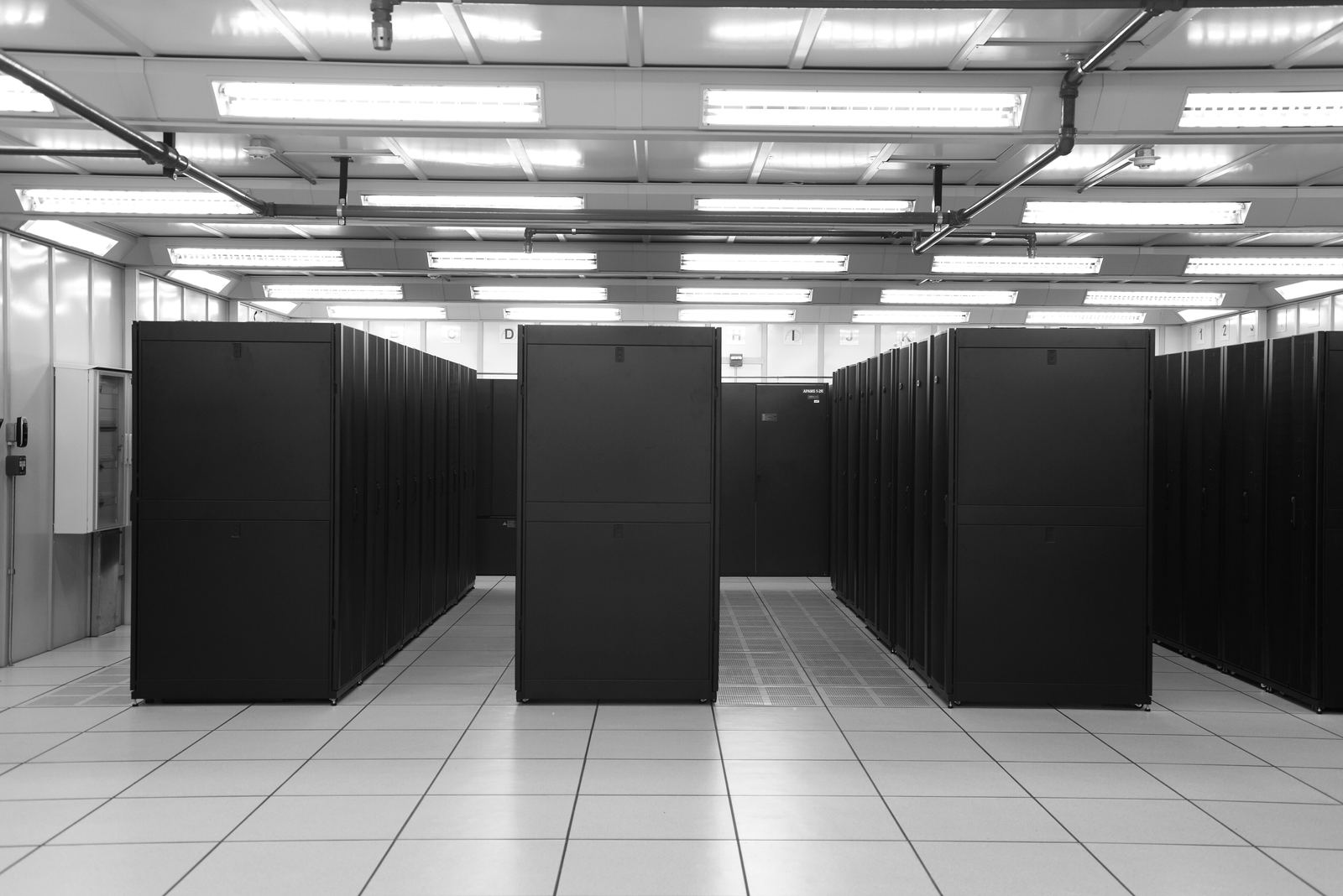An aisle in a data centre between rows of black server cabinets