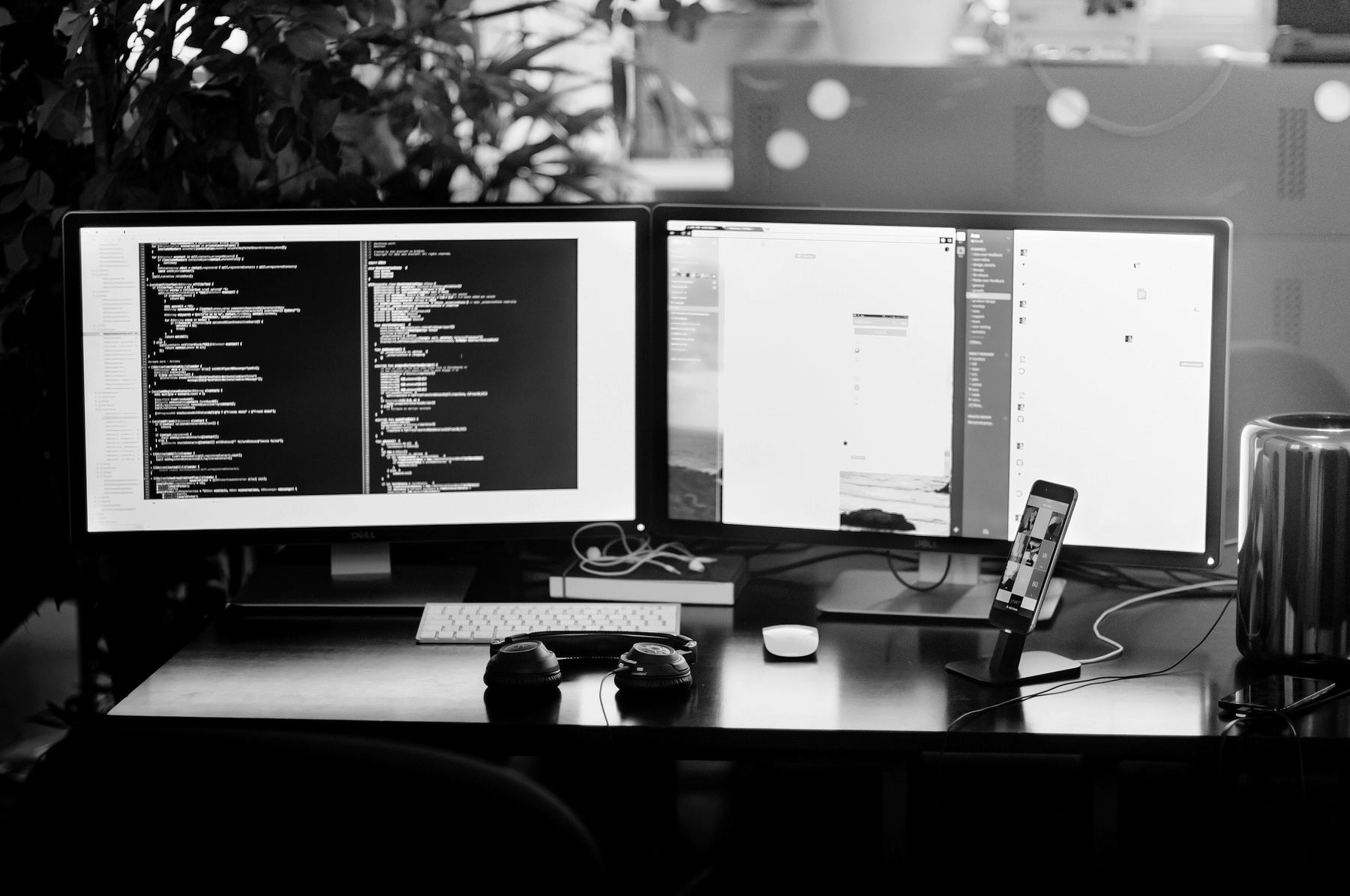 A desk with two screens of code, a keyboard and a phone
